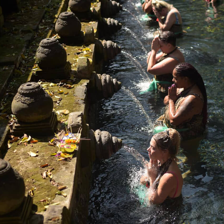 women at The Phoenix Retreat Bali 2023 praying and bathing in Tirta Empul temple holy water