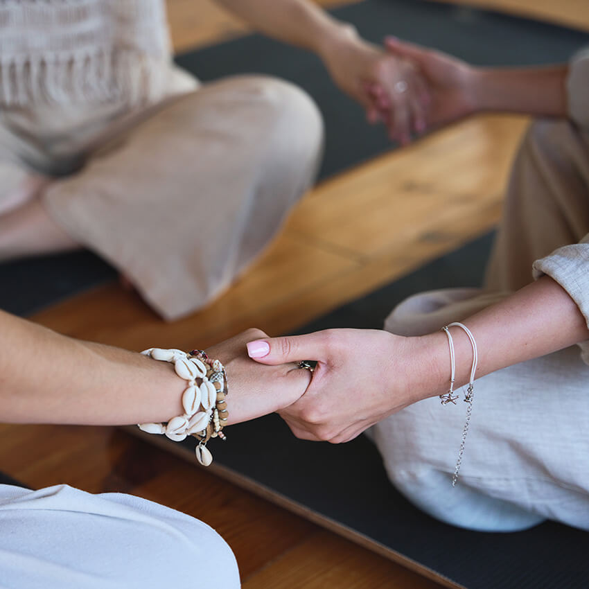 women holding hands in a meditation group at spiritual wellbeing retreat